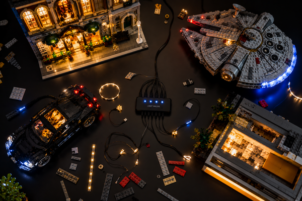 Modèles LEGO illuminés par des kits LED avec câbles et hub USB sur fond noir.